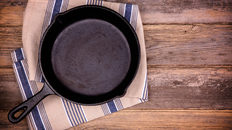 An empty cast iron skillet on a tea towel.