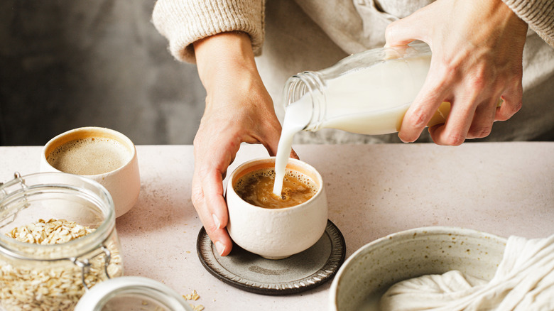 pouring oat milk into coffee at home