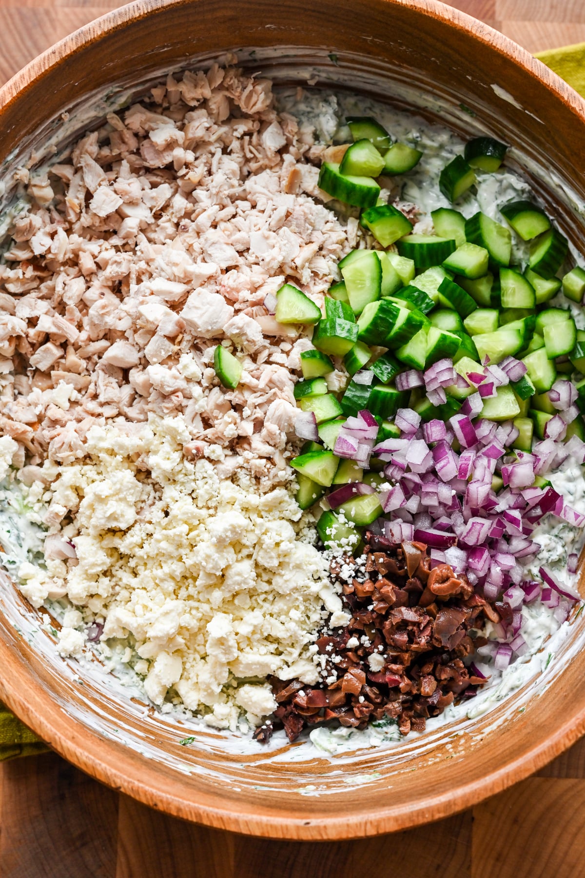 Tzatziki chicken salad ingredients added to the bowl with the dressing.