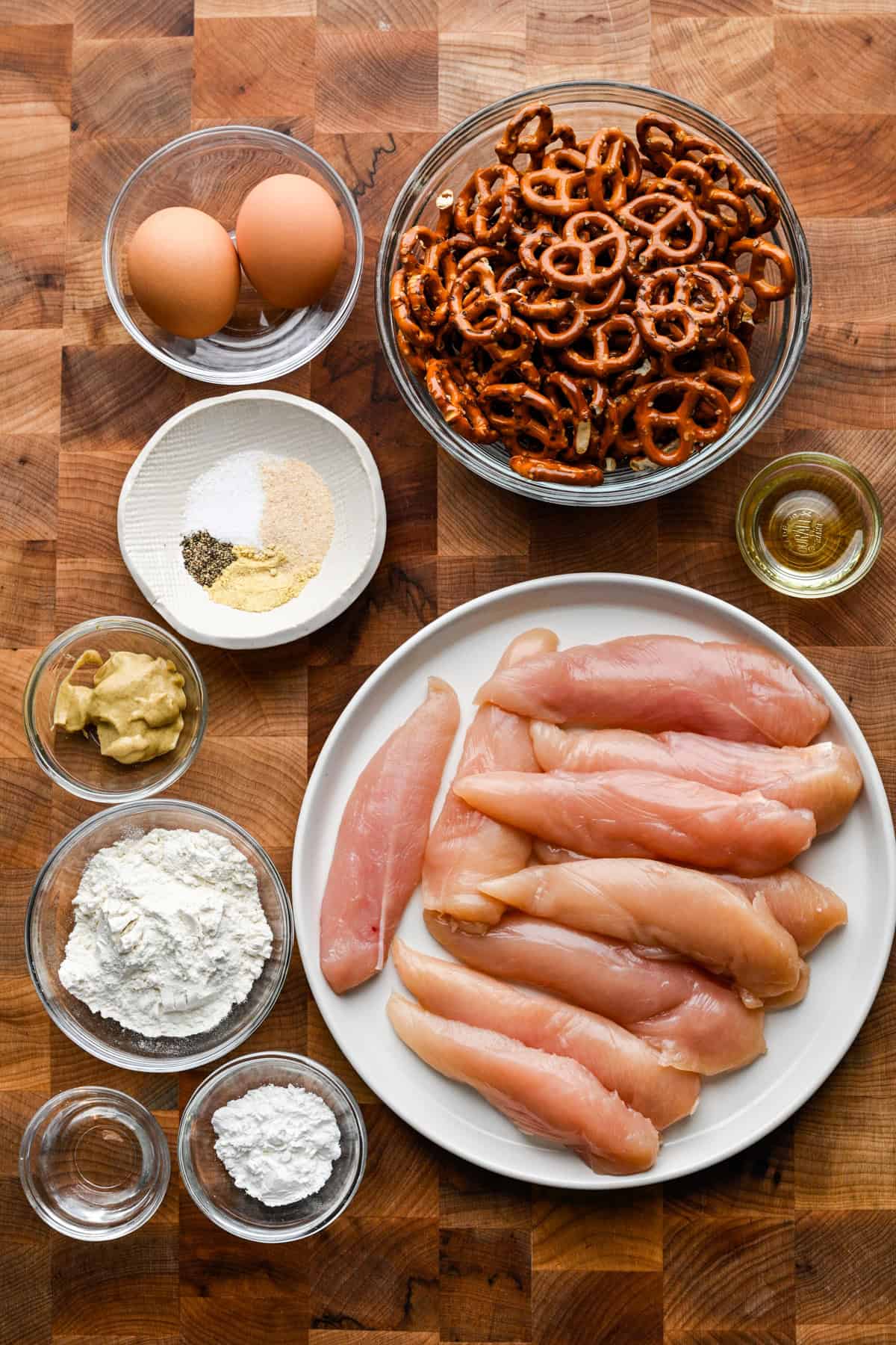 Overhead view of chicken tender ingredients, including chicken, pretzels, and spices.