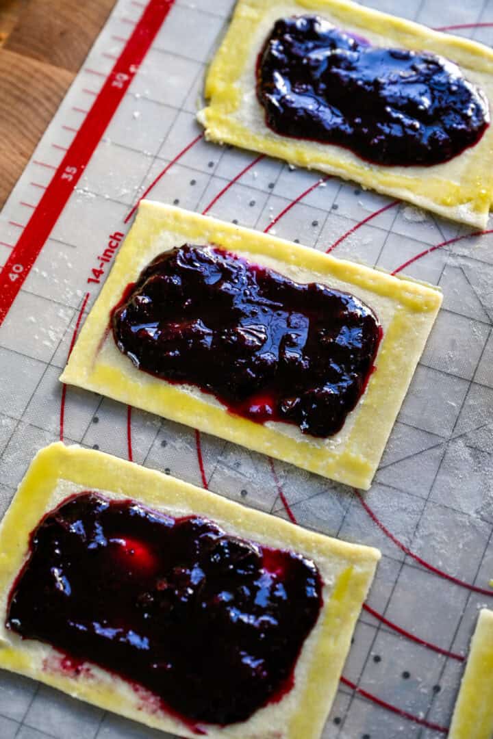 rectangle of pop tart dough topped with blueberry filling and egg wash around the edges. 