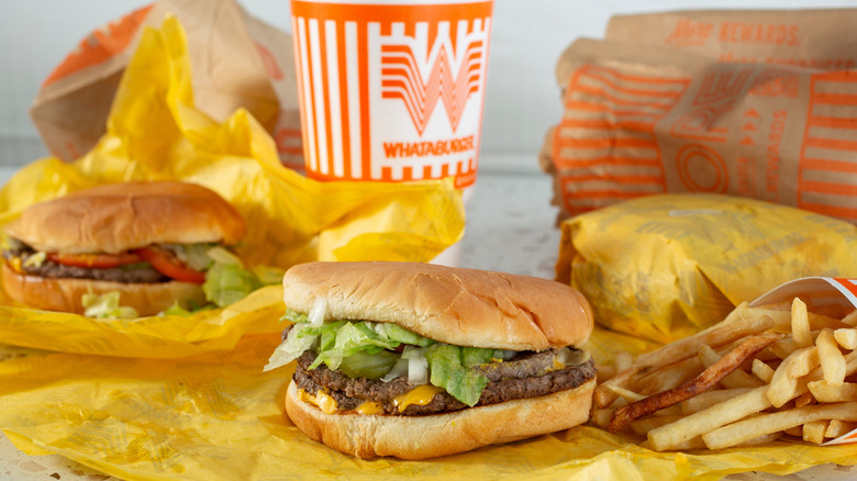 A display of items from Whataburger including two unwrapped burgers, a wrapped item, a drink, and fries