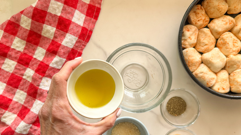 hand adding oil to bowl