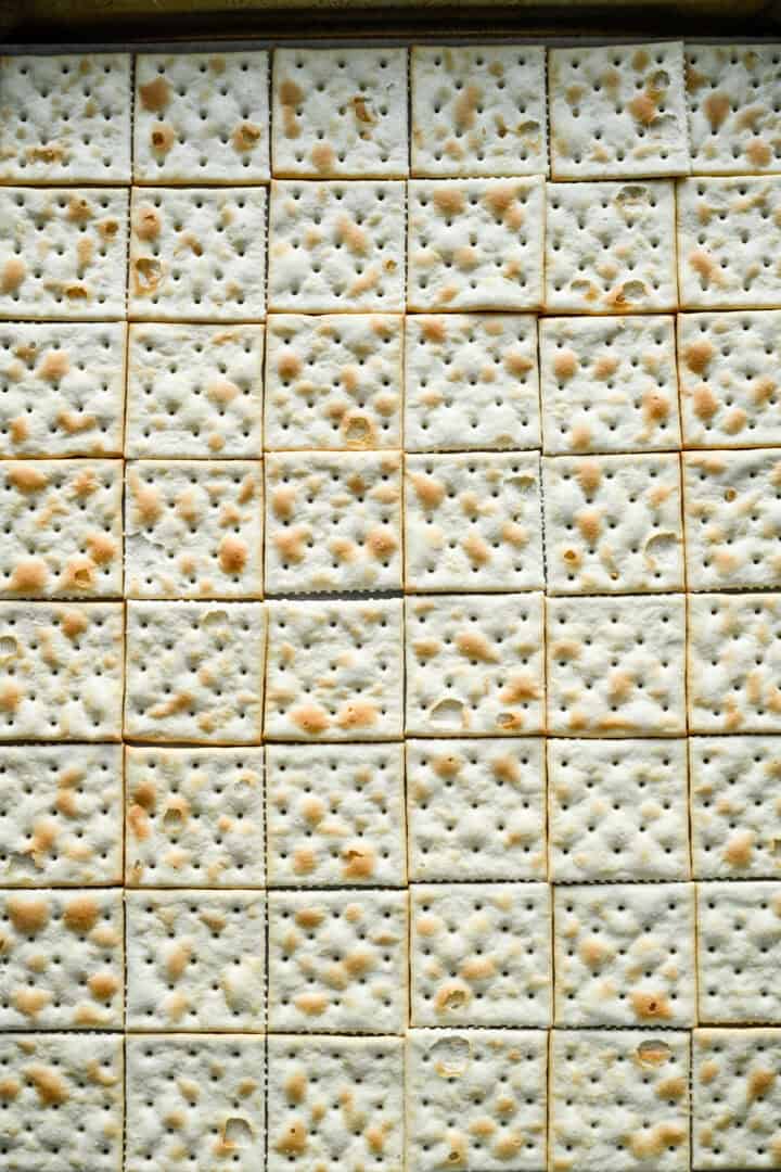 Overhead view of saltines on a sheet pan.