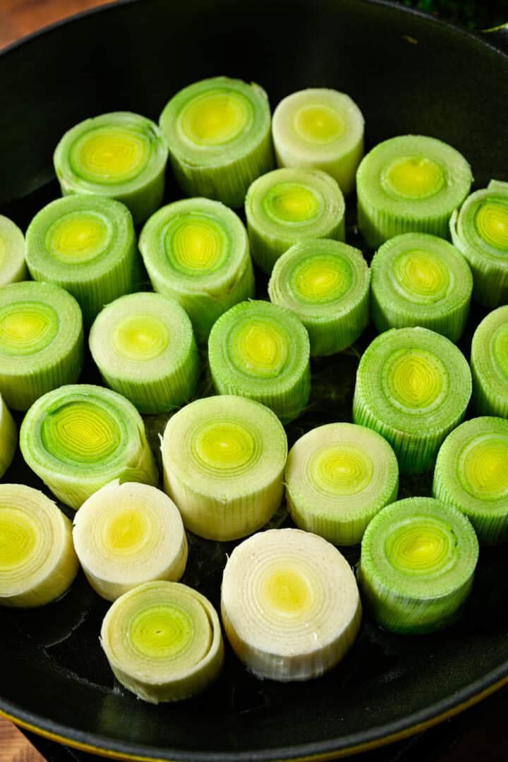 Overhead view of raw leeks in a pan.