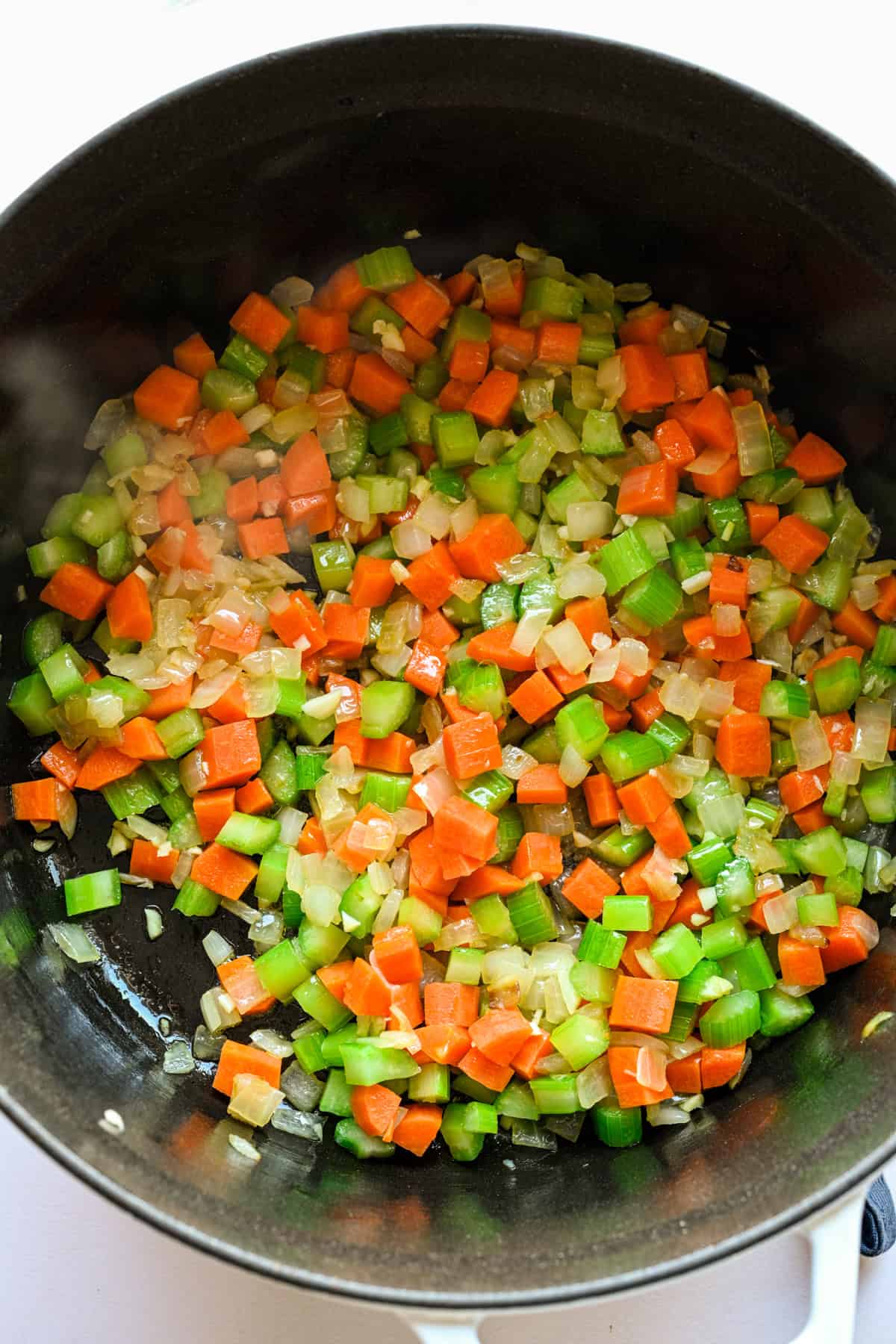Vegetables sautéing in a large pot.