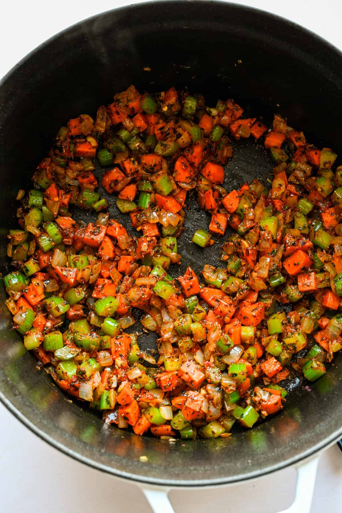 Tomato paste and seasonings added to the vegetables in the pot.