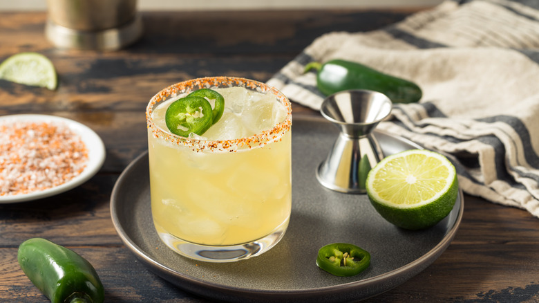 Spicy margarita with a Tajín rim and sliced jalapeños plus lemon half on the side