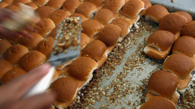 White Castle burgers on the grill with onions underneath them.