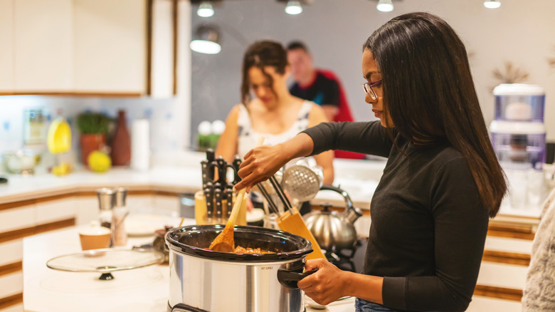 woman stirring food in a slow cooker