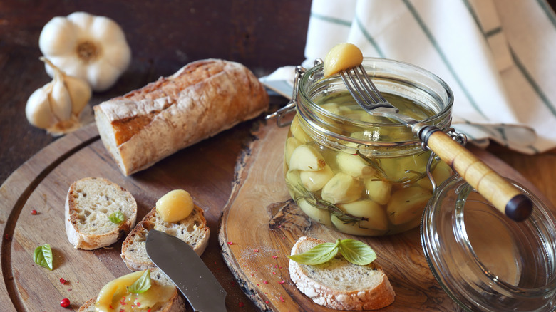 Garlic confit in a jar on a table.
