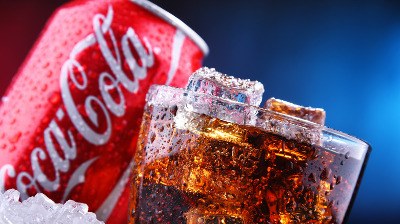 Close up of a glass of Coke in front of its can