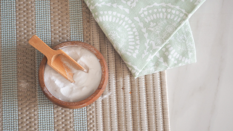 Bowl of baking soda on a mat next to a cleaning cloth