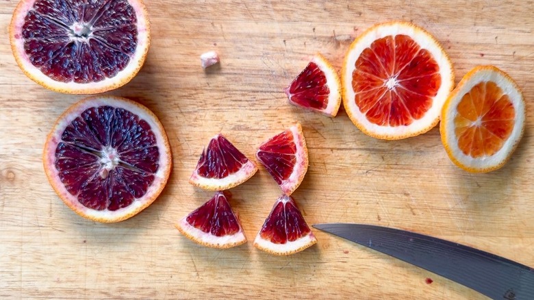 Cutting slices from blood orange on cutting board