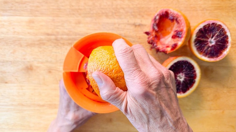 Juicing blood oranges on cutting board