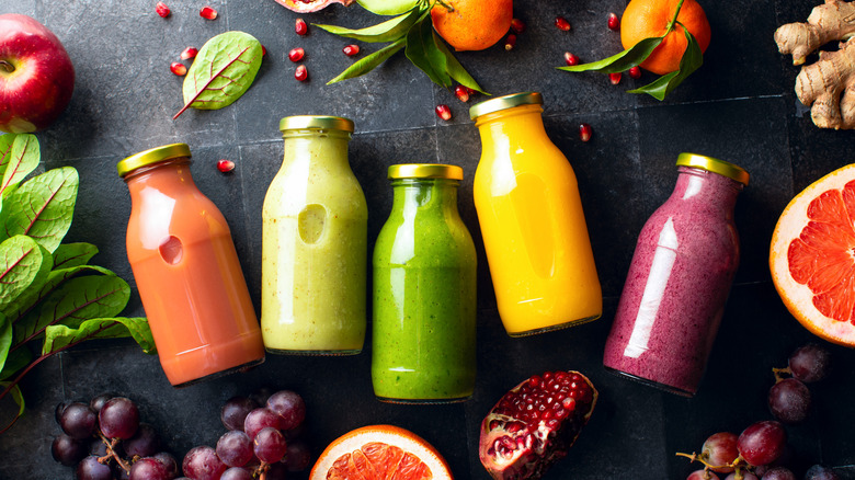 Various colorful fresh raw ingredients and already blended mix in a bottles