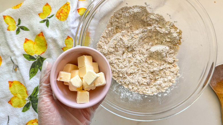 hand adding butter to bowl