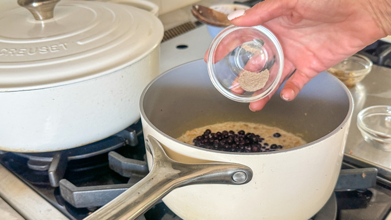 hand adding spices to pot