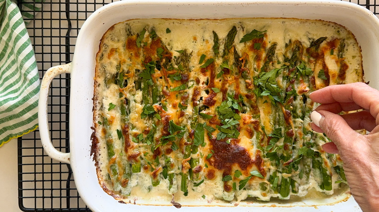 hand adding parsley to casserol