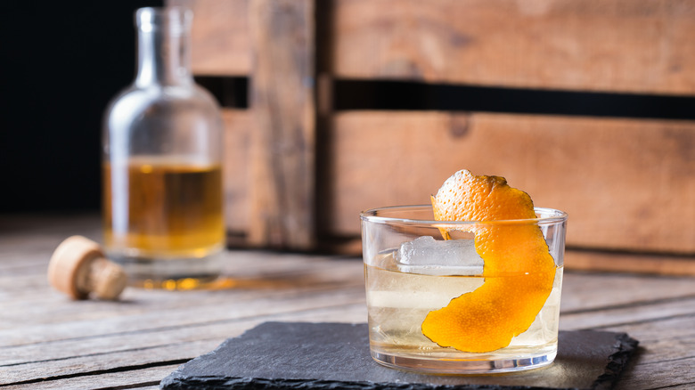 Oaxaca old fashioned with bottle of mezcal in the background