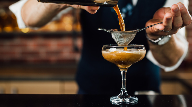 Bartender straining an espresso martini into a coupe glass