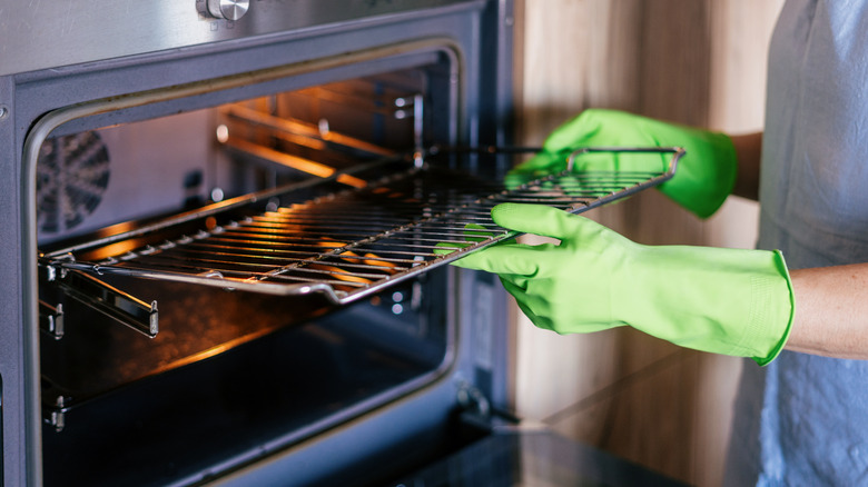 A person taking out an oven rack from an oven