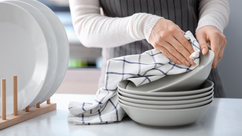 woman wiping a plate with a towel in a kitchen