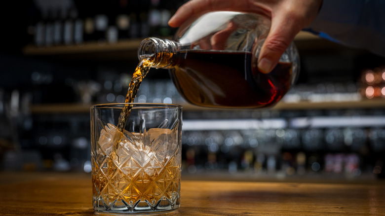 An individual pouring scotch into a glass.