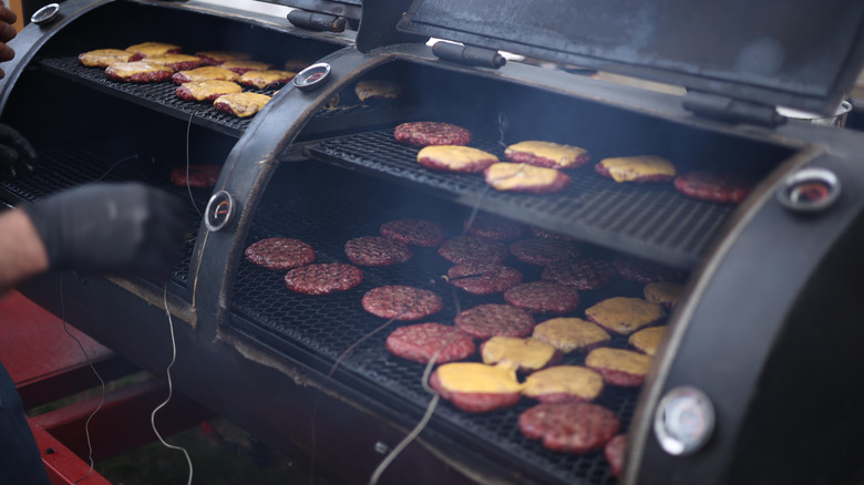 An array of patties being cooked on a smoker.
