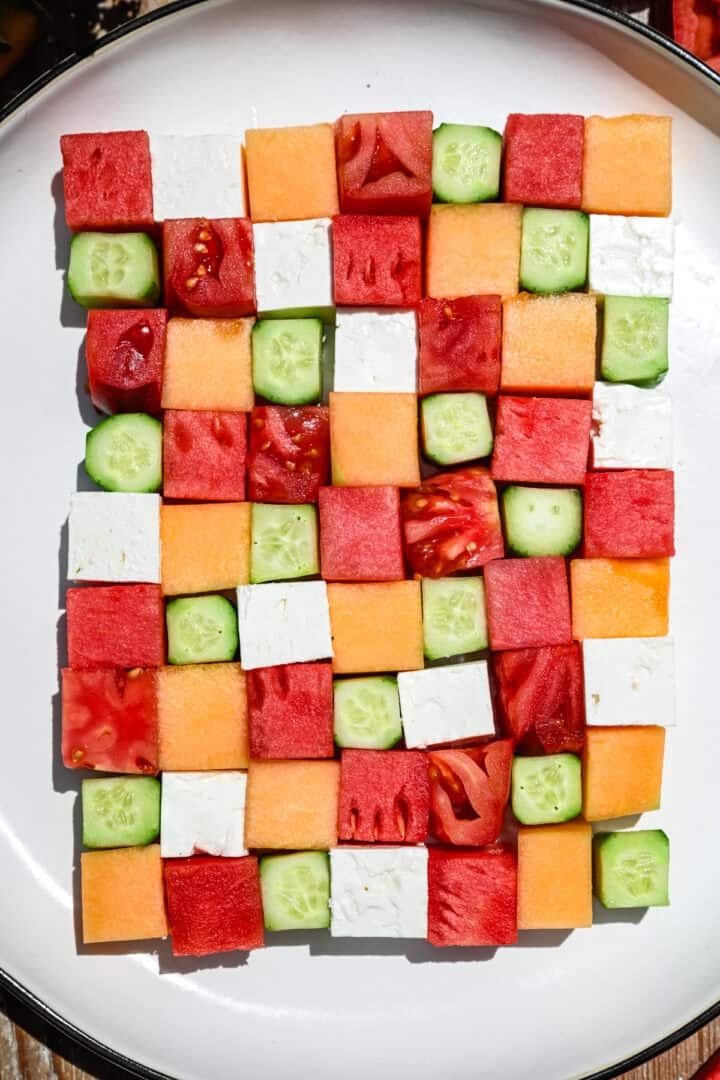 overhead view of watermelon checkerboard salad with squares of melon, cucumber, tomato and feta.