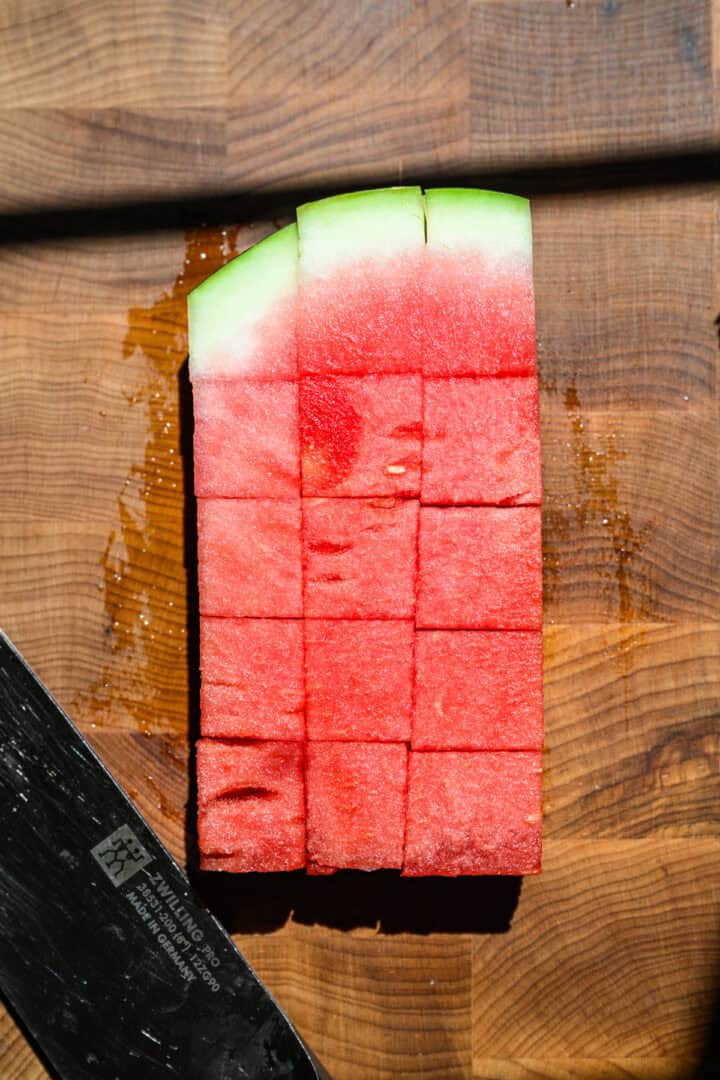 dicing 3 sticks of watermelon into 1 inch cubes.