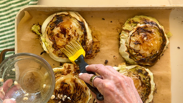 hand brushing roasted cabbage steaks with oil