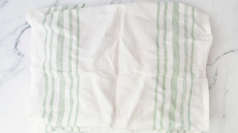 A clean kitchen towel cover a baking sheet
