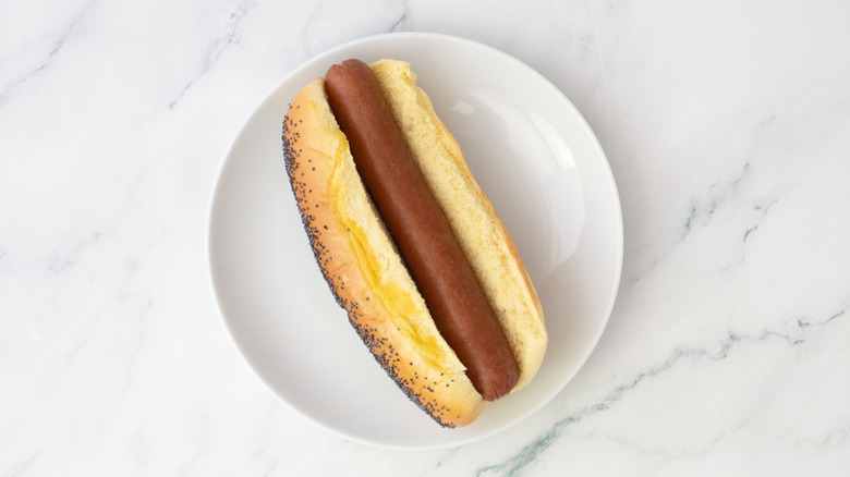 Hot dog in a bun on a white plate
