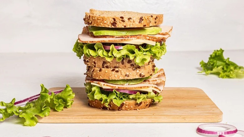 two DIY Viral Sprouts Sandwiches stacked on a wooden cutting board