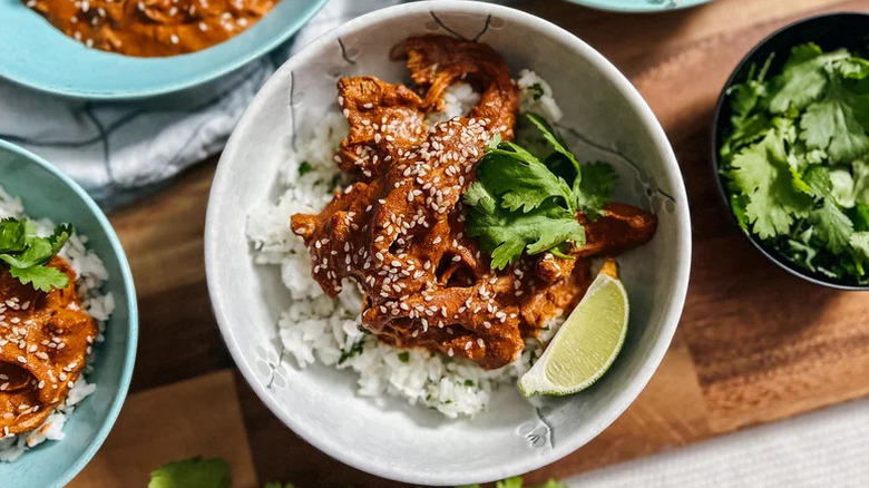 a bowl of white rice with Slow Cooker Chicken Mole and a lime wedge