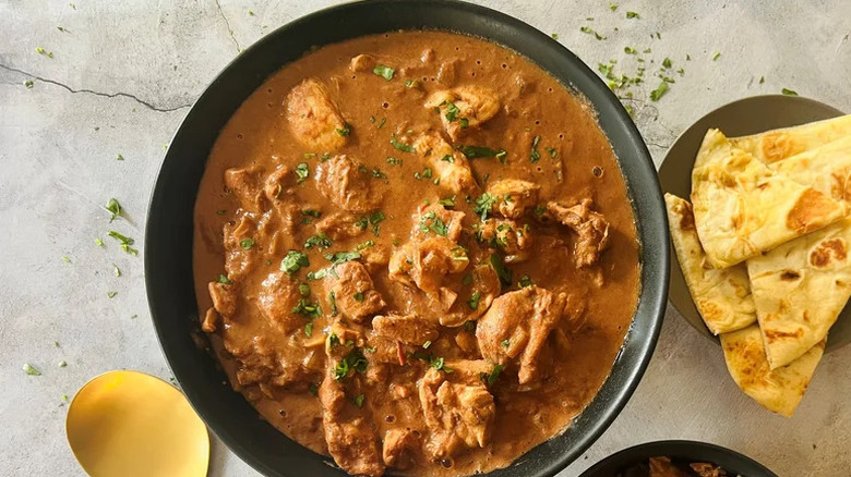 a bowl of Crockpot Butter Chicken with a plate of naan