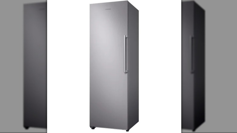upright gray freezer on plain background