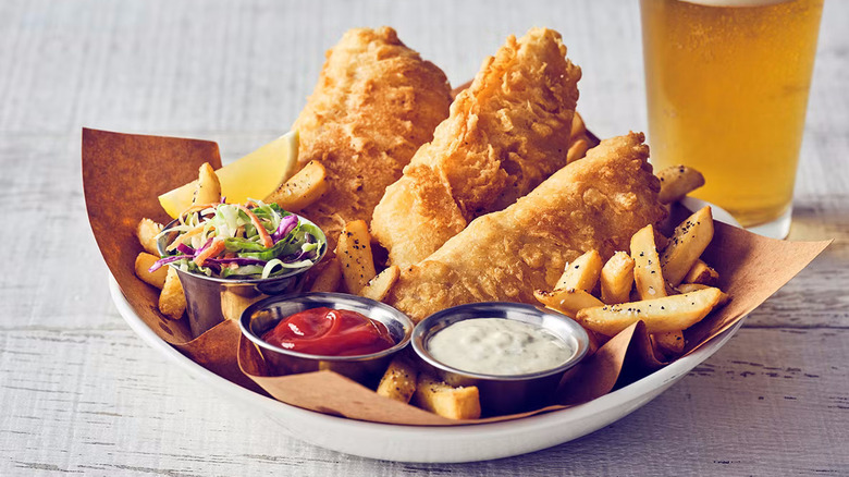 Bonefish Grill fried fish with fries, slaw, and tartar sauce in a paper-lined bowl next to a beer