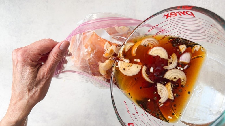 Pouring sambal matah-ish brine into ziplock bag with pork chops