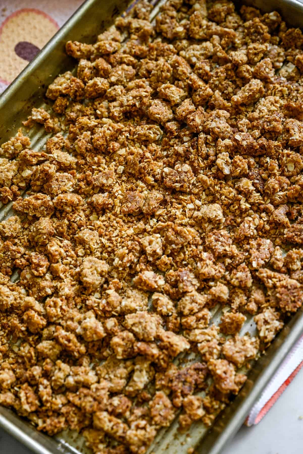 Overhead view of peach crisp broken apart on a sheet pan.