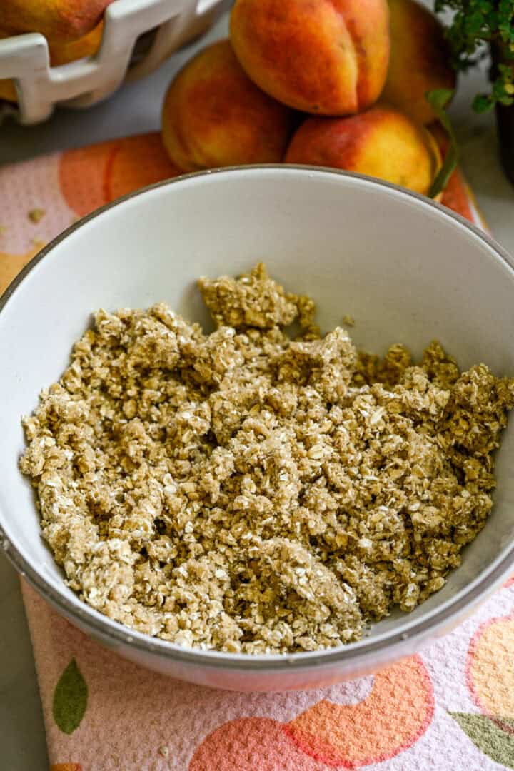 Overhead view of peach crisp ingredients in a white bowl.