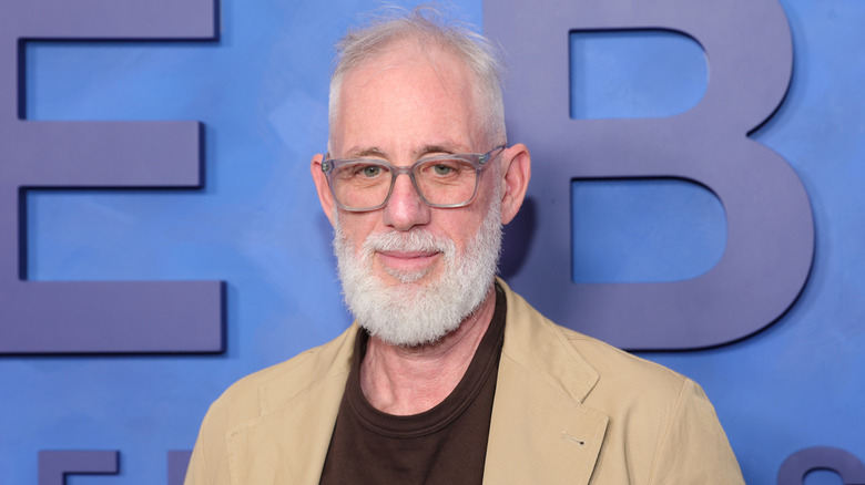Actor Brian Koppelman wearing glasses in front of a blue wall.