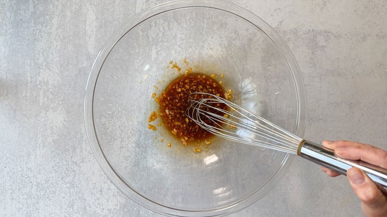 Whisking a marinade for sesame chicken in a large glass bowl