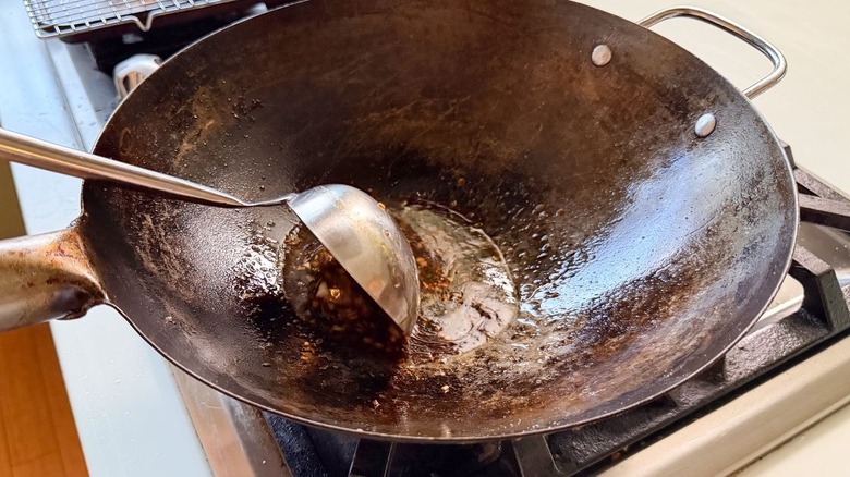 Stirring sauce for sesame chicken in wok on stovetop