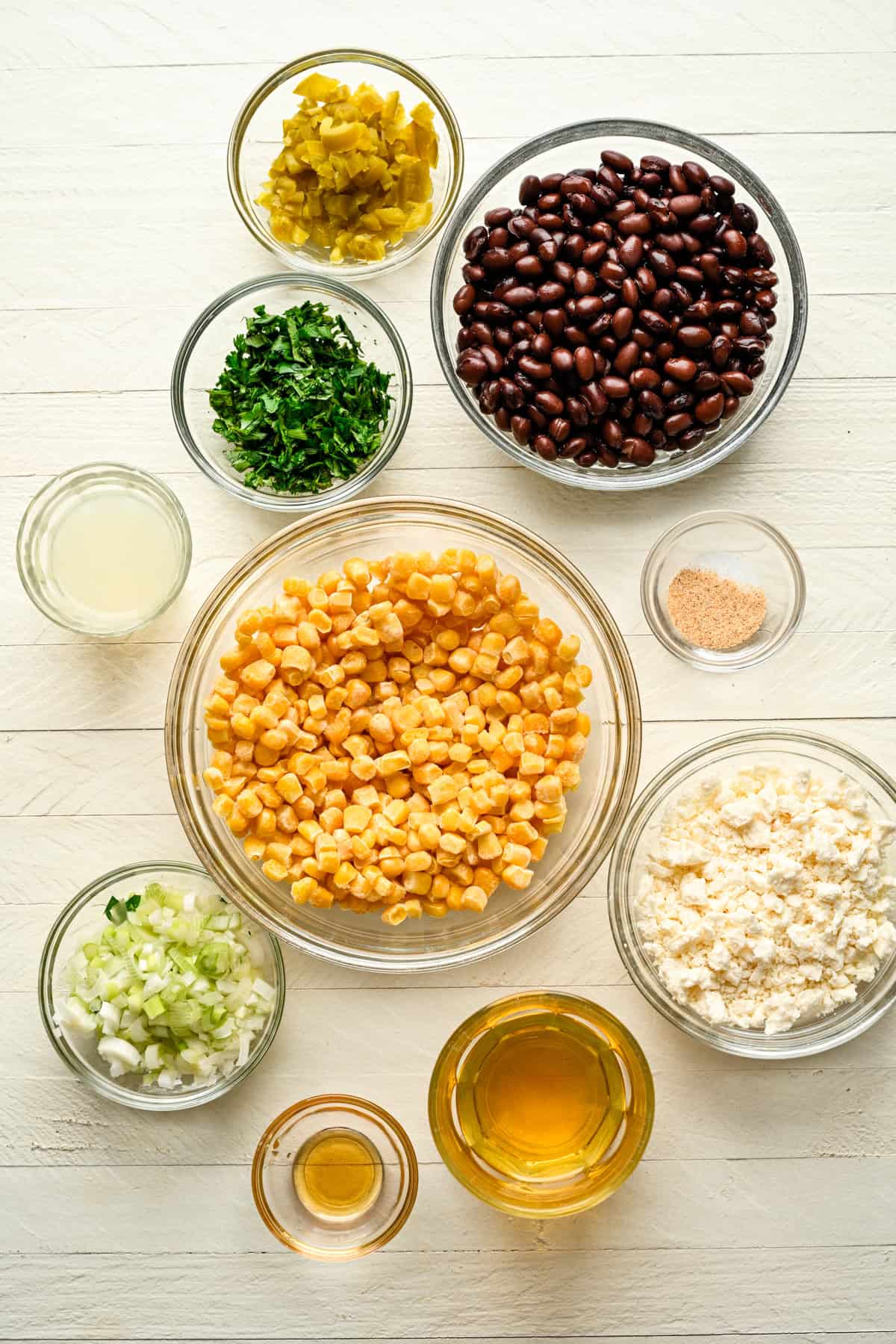 overhead view of ingredients for black bean feta corn dip in separate bowls. 