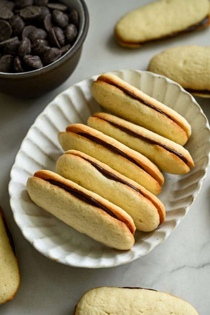 45 degree view of a stack of homemade milano cookies in a white oval bowl.