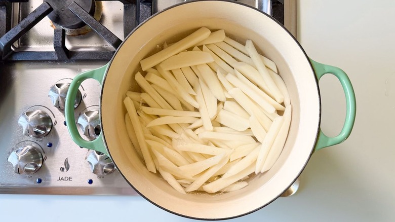 Peeled potato batons in large pot of water on stovetop