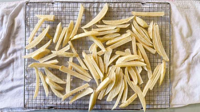 Lightly fried potato batons on rack over kitchen towels