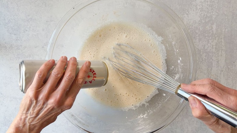 Whisking beer into fish batter in large glass bowl
